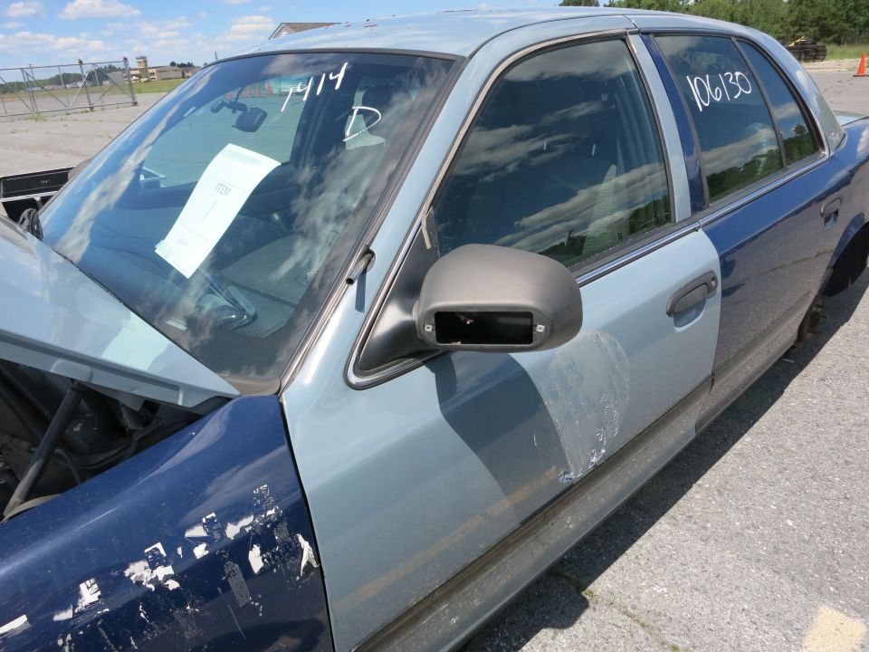 Blue and gray Ford Crown Victoria with a missing side mirror and peeling paint on the fender