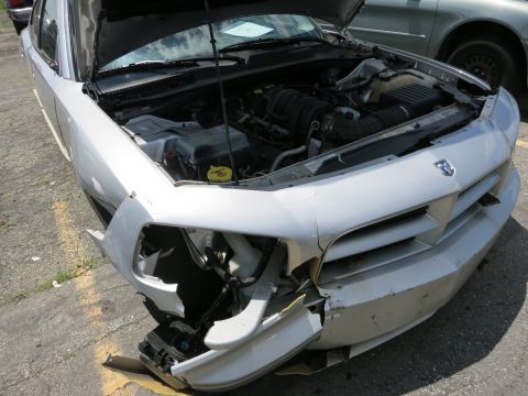 1991 Ford LTD Crown Victoria - Silver Dodge Charger with significant front-end damage and hood open, parked next to another vehicle.