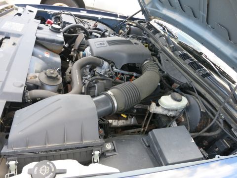1991 Ford LTD Crown Victoria - The engine bay of a blue 1991 Ford Crown Victoria LTD is visible with the hood raised.