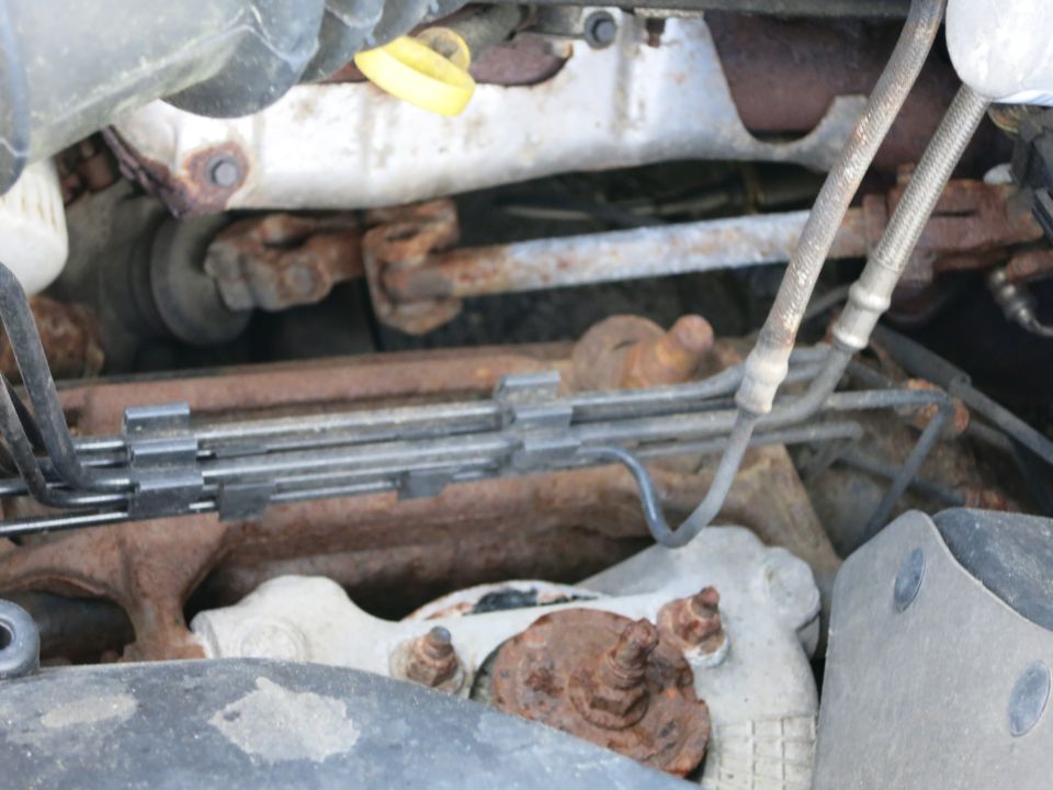 Engine bay with rusty steering linkage and brake lines