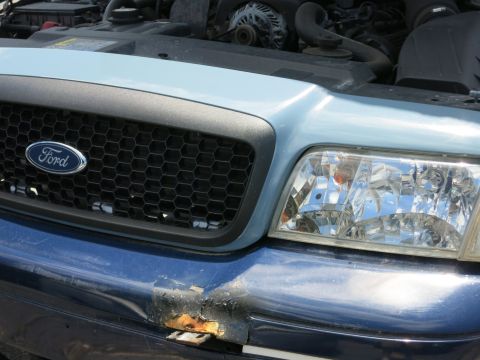 1991 Ford LTD Crown Victoria - Front view of a Ford Crown Victoria showing the grille, headlight, and damaged bumper.