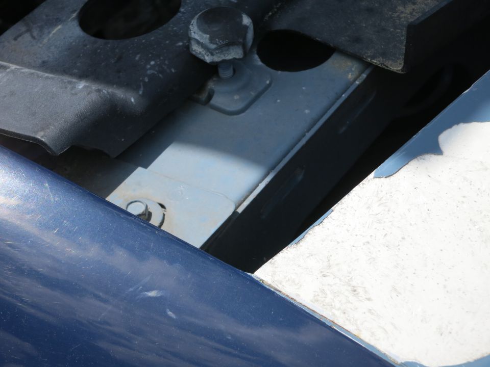 Blue car fender and black engine bay components with bolts and brackets