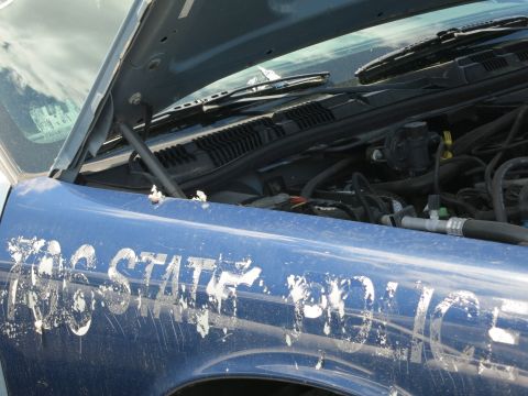 1991 Ford LTD Crown Victoria - Close-up of a blue police car fender with "STATE POLICE" text, revealing the engine compartment.