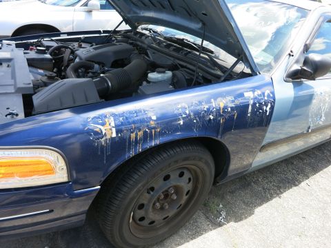 1991 Ford LTD Crown Victoria - The fender of a blue 1991 Ford Crown Victoria LTD has damage and remnants of decals.