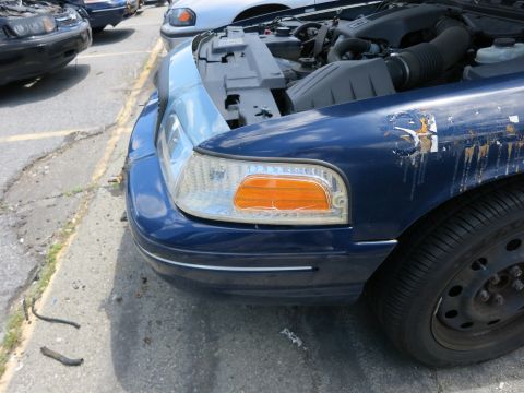 1991 Ford LTD Crown Victoria - A blue sedan with its hood open, revealing the engine compartment and a damaged fender.