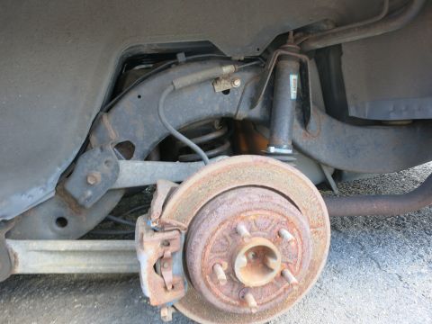1991 Ford LTD Crown Victoria - Close-up view of the rear suspension and brake assembly, showing a rusty rotor and caliper.