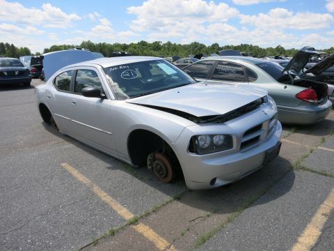 1991 Ford LTD Crown Victoria - Junkyard Dodge Charger missing a wheel and with its hood up, parked next to other vehicles.