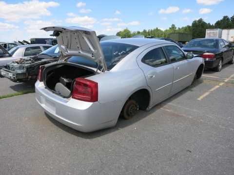 1991 Ford LTD Crown Victoria - A silver sedan sits in a junkyard with its trunk open and missing wheels.