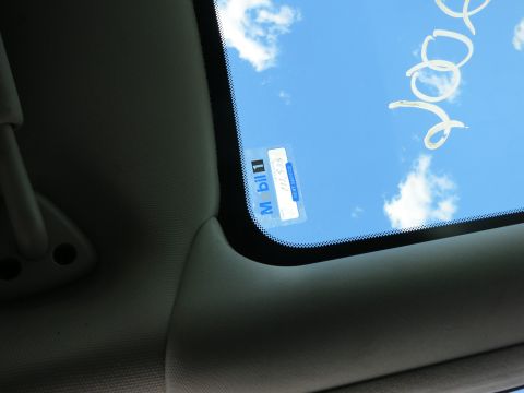 1991 Ford LTD Crown Victoria - View through the car windshield shows a Mobil 1 sticker and handwritten text against a bright blue sky with clouds.