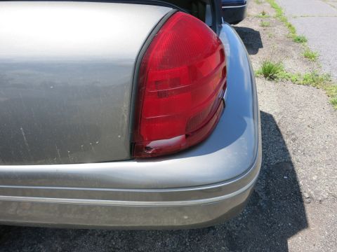 1991 Ford LTD Crown Victoria - Close-up view of the rear taillight and bumper of a silver vehicle, with another car partially visible in the background.