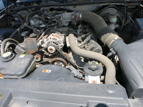 1991 Ford LTD Crown Victoria - The engine bay of a 1991 Ford Crown Victoria LTD reveals its internal components, including the alternator and various hoses.