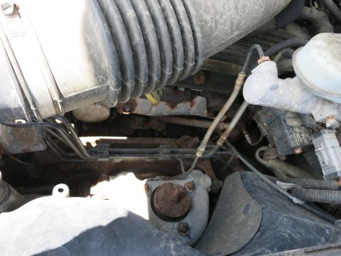 1991 Ford LTD Crown Victoria - Close-up view of the engine bay, showing the air intake hose, brake fluid reservoir, and exhaust manifold.