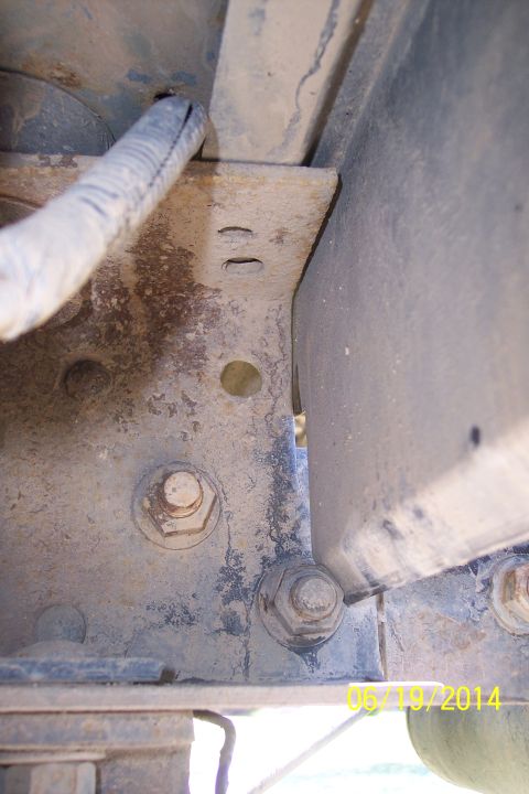 1990 Ford Bronco - A close-up view of a vehicle's frame and wiring harness, showing bolts and dirt.
