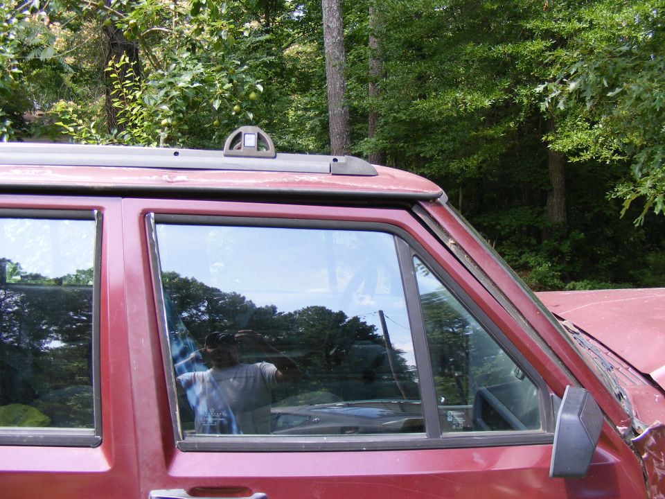 Red SUV side view, showing roof rack and window reflections