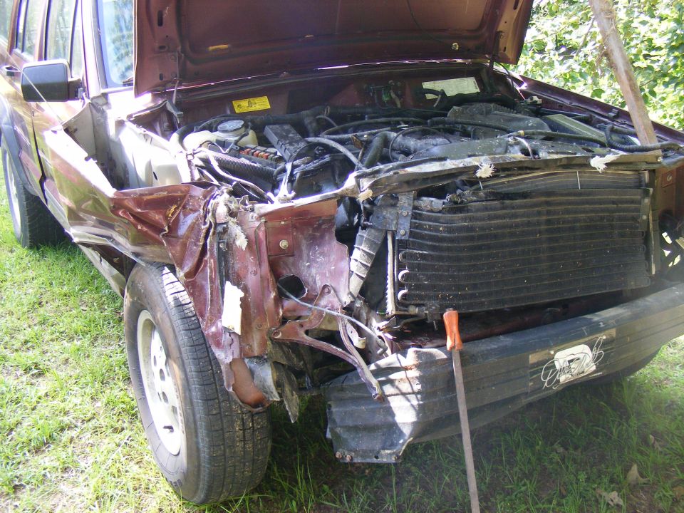 Maroon SUV with severe front-end damage, hood open, engine exposed, grille damaged