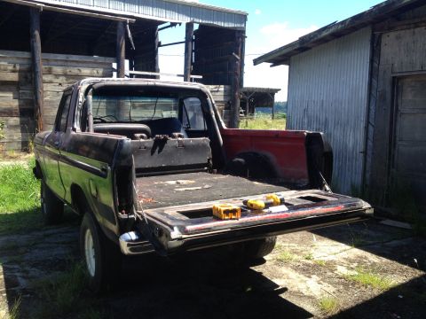 1978 Ford Bronco - This Bronco appears to be a project vehicle, with its bed open and tools visible, parked in a rural setting.