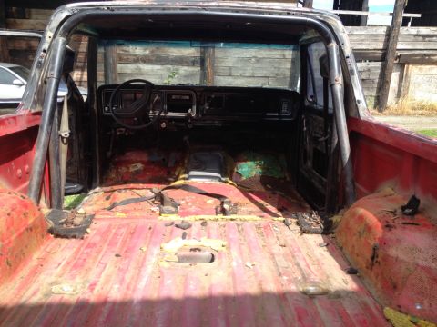 1978 Ford Bronco - The interior of a red 1978 Ford Bronco shows a roll cage and a worn interior, suggesting it may be undergoing restoration.