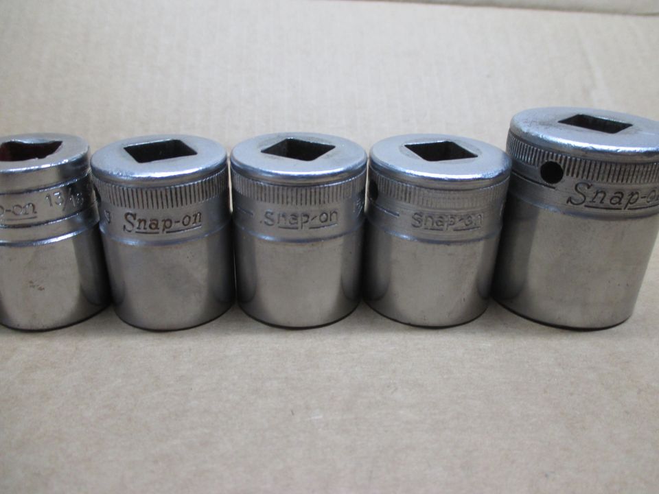 Five metal Snap-on sockets of varying sizes arranged in a row on a textured surface