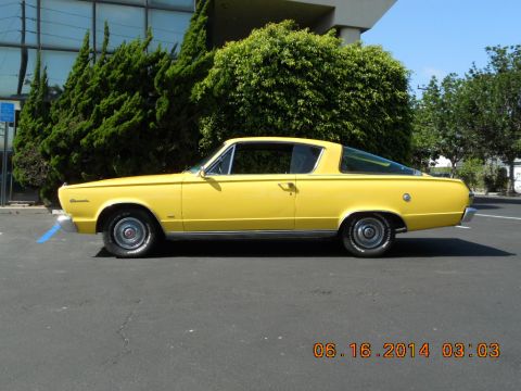 1966 Plymouth Barracuda - A yellow coupe is parked in a lot with trees and a building in the background. A date stamp is visible in the lower right corner.