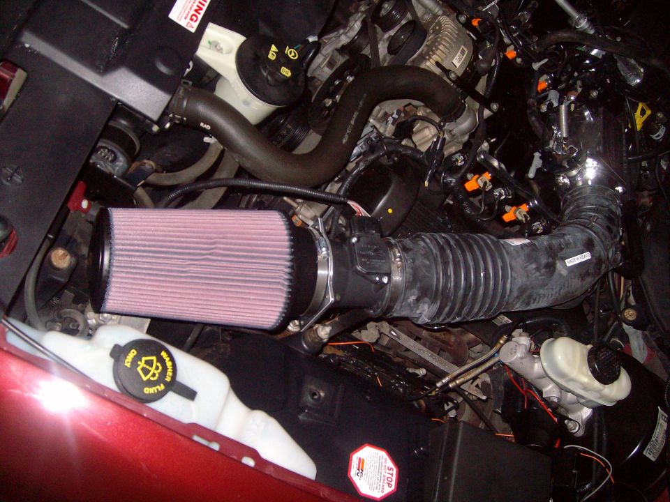 Engine bay with red fender, K&N air filter, and black hoses