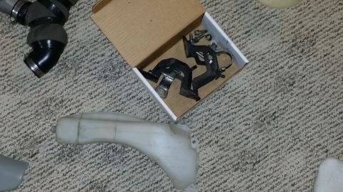 2007 Subaru Impreza - Various automotive parts, including hoses and brackets, are displayed on a carpeted surface.