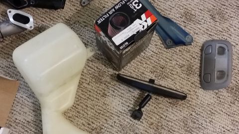 2007 Subaru Impreza - A collection of automotive parts, including an air filter and reservoir, are laid out on a carpeted floor.