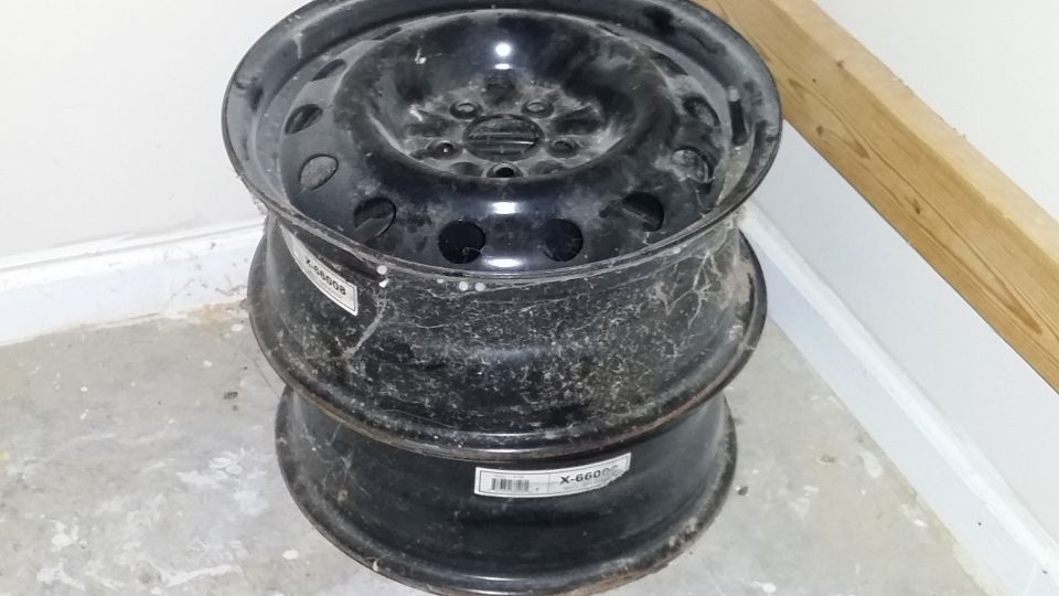 Two black steel wheels stacked on a concrete floor, with labels visible