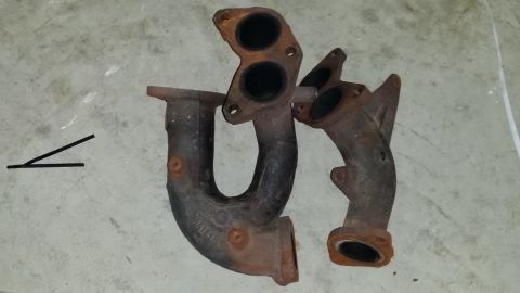 2007 Subaru Impreza - Two exhaust manifold sections are shown on a concrete surface.