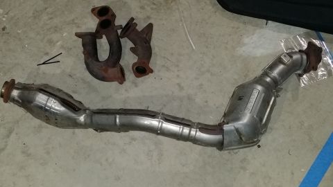 2007 Subaru Impreza - Exhaust manifold and catalytic converter parts are laid out on a concrete surface.