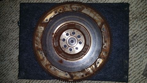 2007 Subaru Impreza - A rusty flywheel is shown, with a bearing visible in its center, placed on a dark mat.
