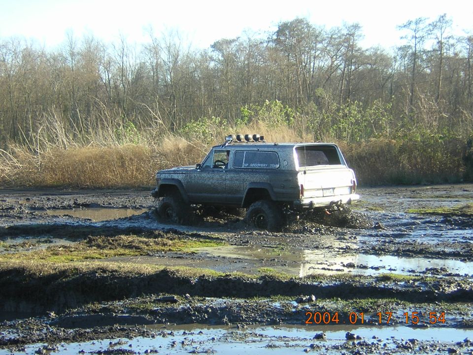 Muddy SUV stuck in a swampy area with trees in the background