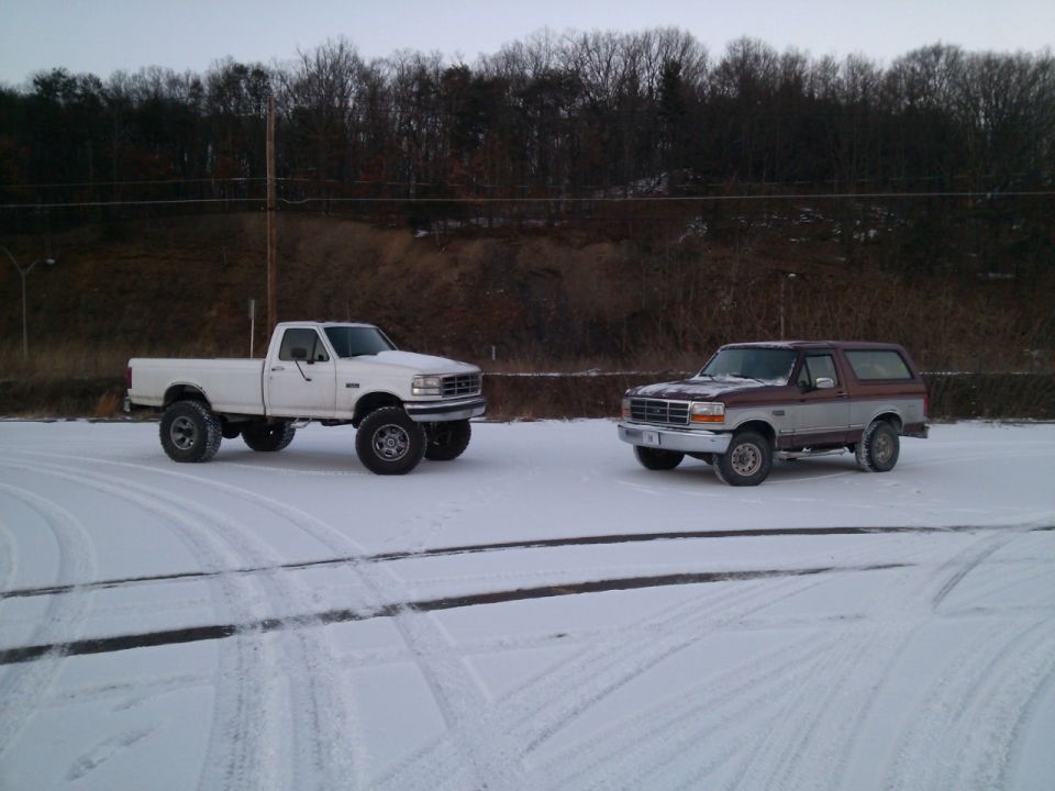 White 1995 Ford F-350 and maroon/silver Ford Bronco in snow