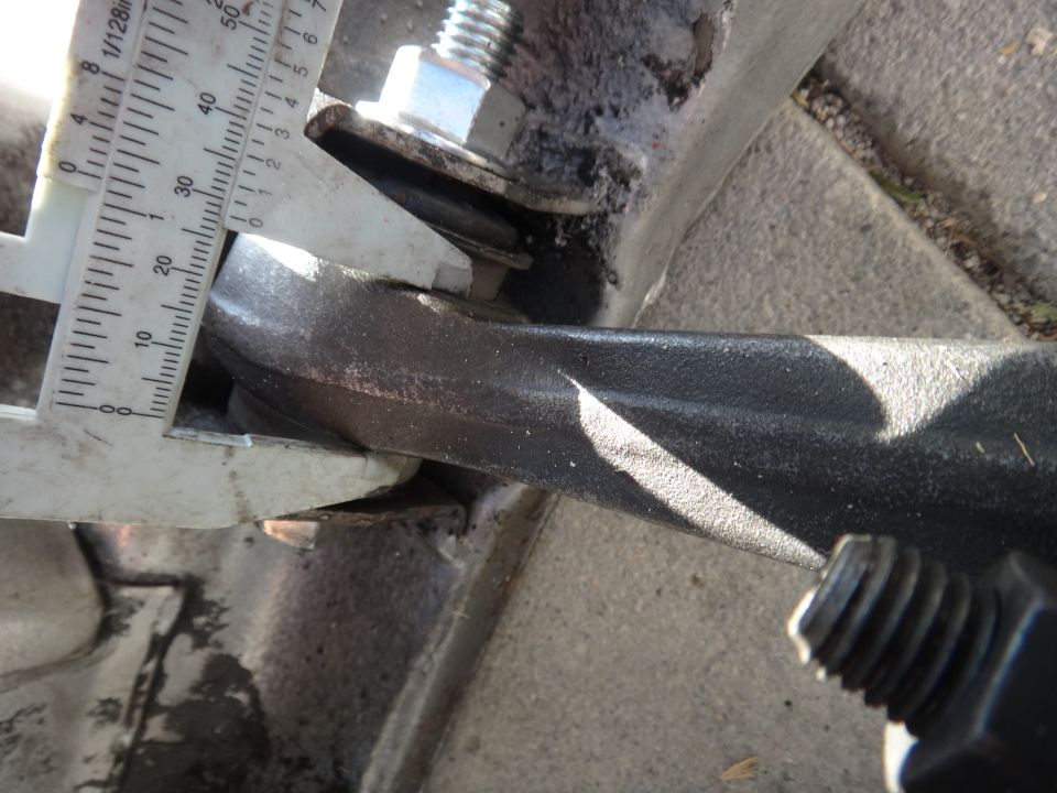 Caliper measuring the thickness of a black metal automotive part. Scale shows approximately 25mm