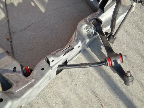1993 Ford Taurus - Close-up of a car's front suspension subframe and components, including a sway bar and control arm.