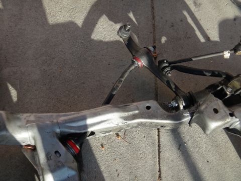 1993 Ford Taurus - Close-up of a vehicle's front suspension subframe assembly, showing control arms and steering components.