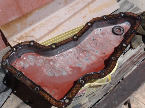 1993 Ford Taurus - An oil pan with a gasket is shown, containing red fluid and white residue.