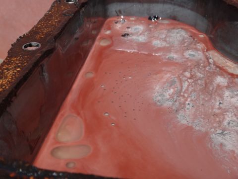 1993 Ford Taurus - Oil pan interior showing accumulated sludge and fluid, likely from an engine.