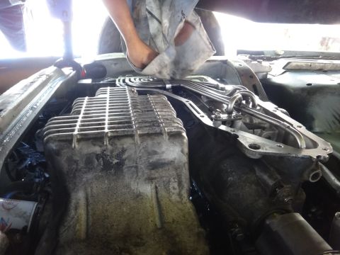 1993 Ford Taurus - Close-up view of engine and transmission parts being serviced, with a hand wiping down the components.