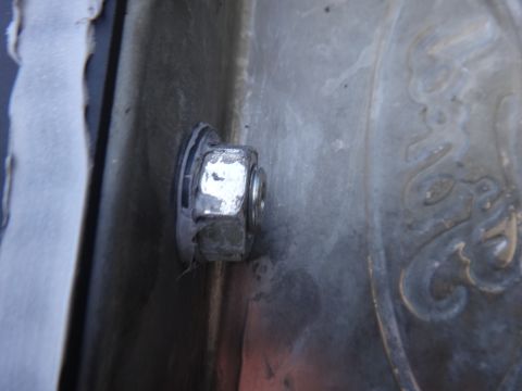 1993 Ford Taurus - A close-up view shows a nut and bolt securing a part to a metal surface with an embossed design.
