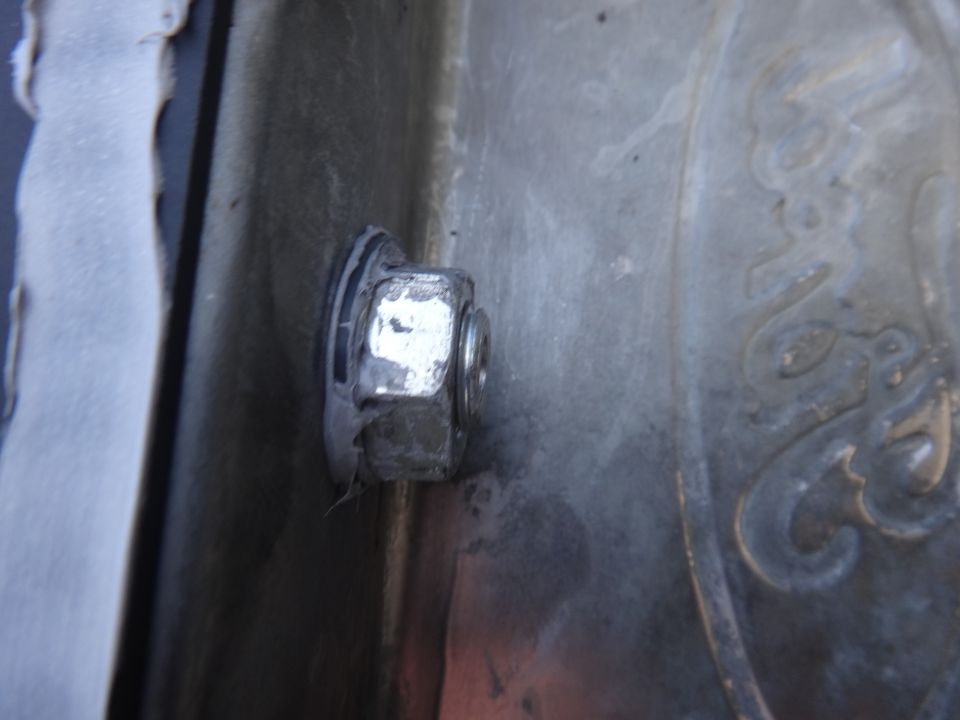 Close-up of a silver nut and bolt assembly on a textured metal surface with a faint embossed pattern