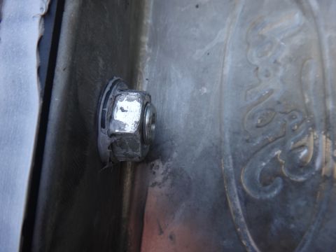 1993 Ford Taurus - A close-up view shows a nut and bolt securing a part to a textured metal surface with embossed lettering.