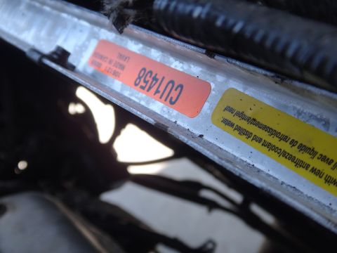 1993 Ford Taurus - Close-up of a radiator showing a CU1458 sticker and a yellow warning label about coolant and distilled water.