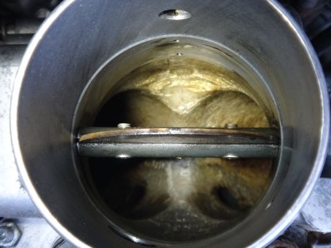 1993 Ford Taurus - Close-up of a throttle body's interior, showing carbon buildup around the butterfly valve.