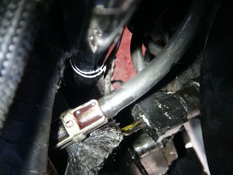 1993 Ford Taurus - Detail of a hose clamp and electrical connector within an engine bay, showing wear and potential fluid leakage.