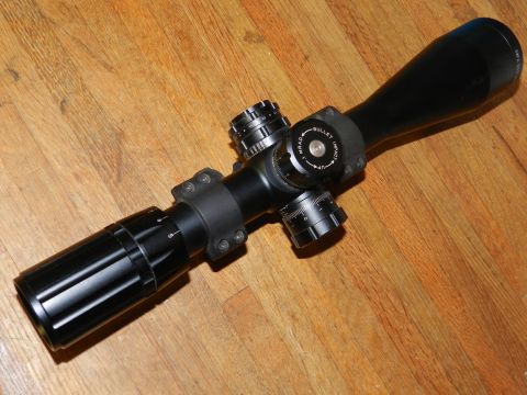 1996 Ford Bronco - Rifle scope with adjustment turrets and objective lens shown on a wooden surface.