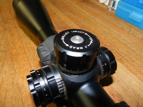 1996 Ford Bronco - A rifle scope with adjustable turrets and markings for windage and elevation is shown on a wooden surface.