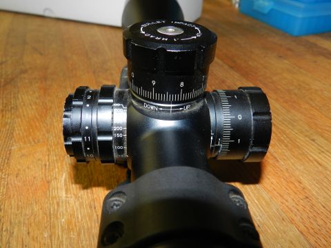 1996 Ford Bronco - Close-up of a rifle scope showing adjustment turrets and numerical markings.