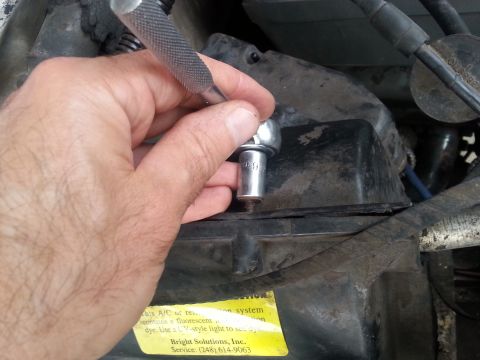 1992 Ford Bronco - A hand uses a socket wrench on a black plastic component, likely part of an automotive repair.