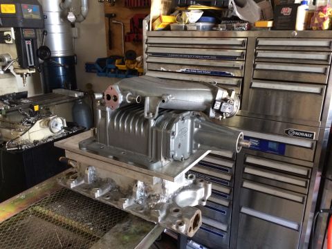 1996 Ford Bronco - A supercharger and engine manifold assembly sits on a workbench in a garage setting.