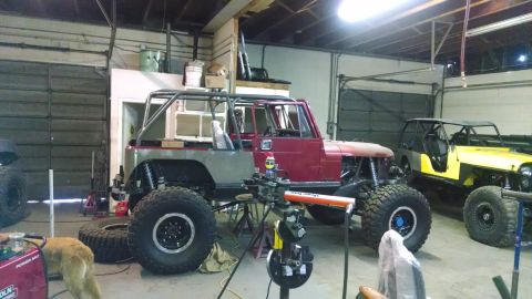 1985 Jeep CJ7 - A heavily modified Jeep CJ is in a garage, undergoing some work, with another Jeep visible behind it.